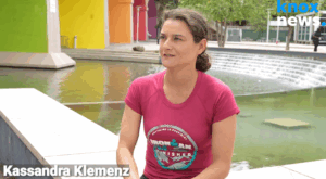 Kassandra Klemenz sitting in front of a fountain being interviewed.